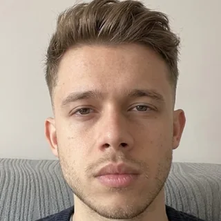 Florian Richter photographed indoors against a pale wall in a navy knit jumper, facing the camera.